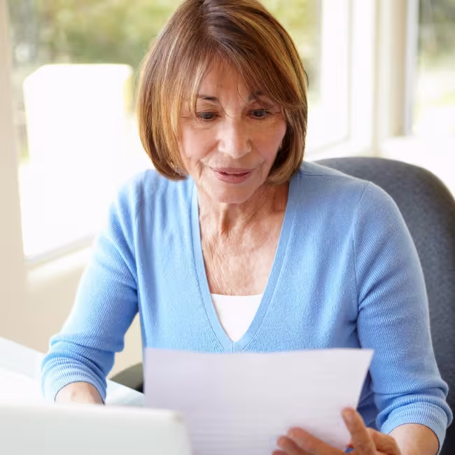 Woman sitting at her computer looking at a paper