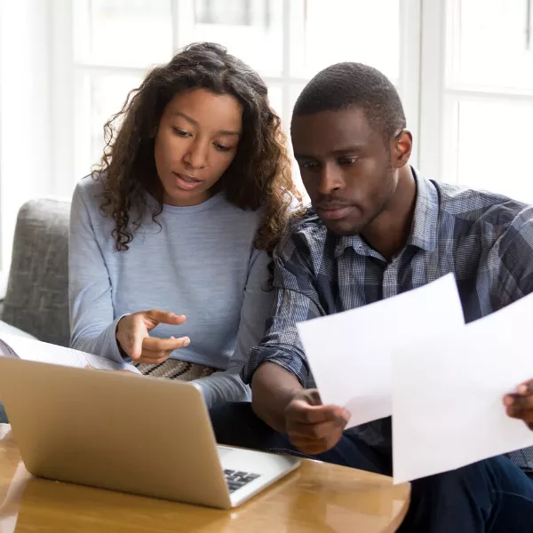 Couple preparing their tax return on a computer while consulting guidance publications