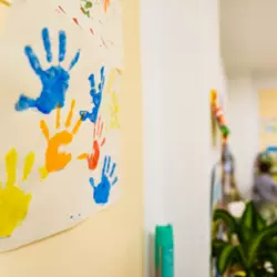 Image of child painted handprints on poster paper in classroom.